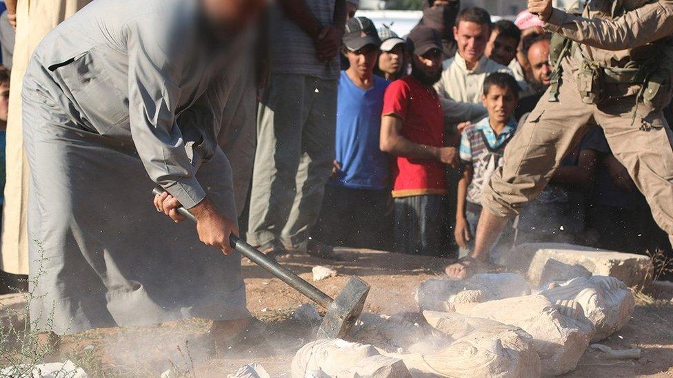 A photo published by Islamic State purportedly showing a militant destroying statues looted from the ancient ruins of Palmyra in Syria (2 July 2015)