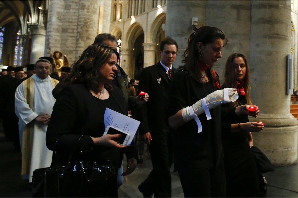 An injured airport worker caries a single candle as she walks in the procession during an ecumenical service for the victims of the Brussels bomb attacks at the Cathedral of St Michael and St Gudula in Brussels, 28 March