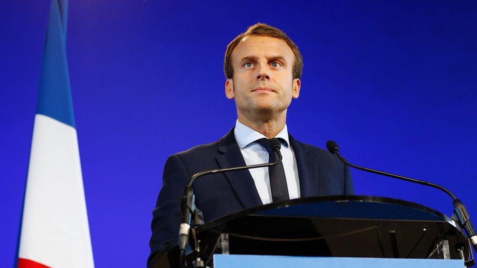 Emmanuel Macron giving a speech in front of a French flag