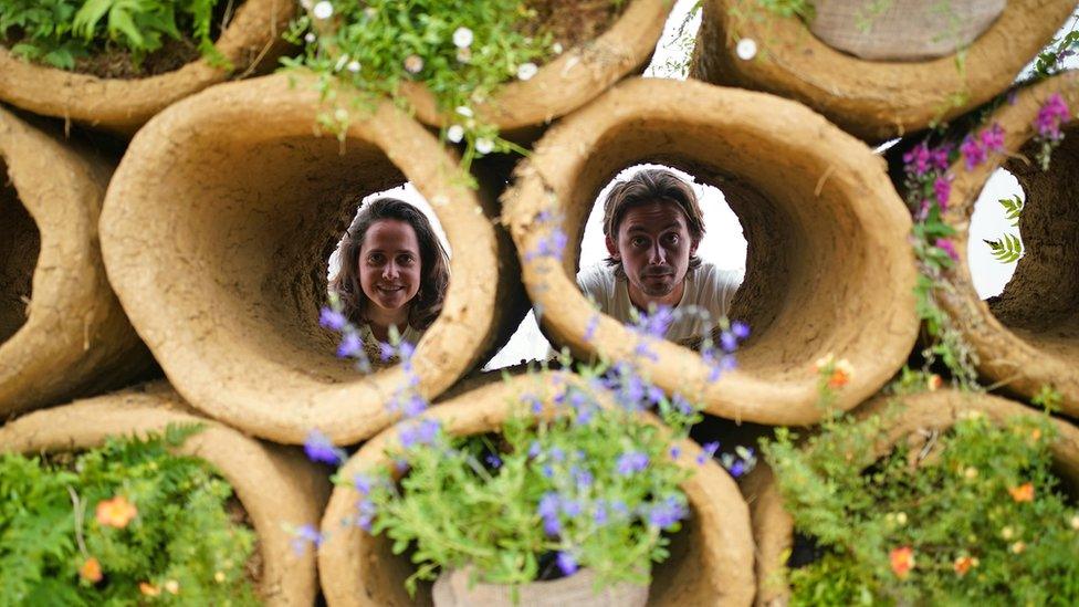 People look through clay tubes.