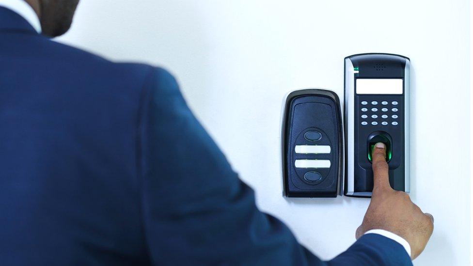 A man using a fingerprint scanner on a wall