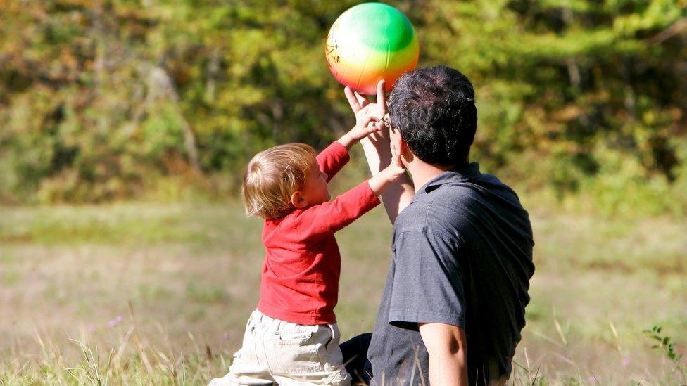 A man playing with a ball with a little boy