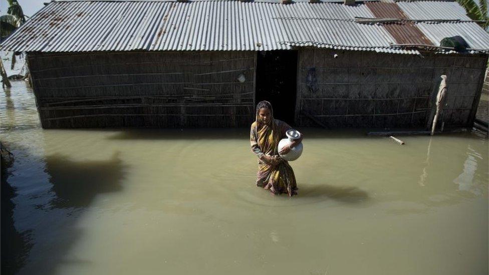 A flood affected woman wades through the water near her partially submerged house in Morigaon district, east of Gauhati, northeastern Assam state,