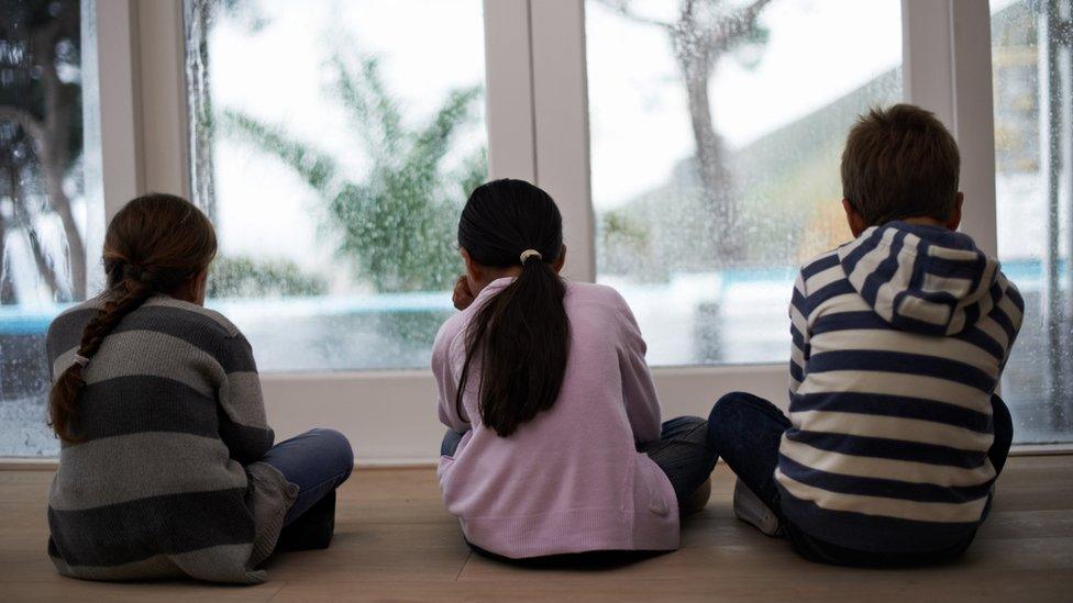 Rainy summer holiday - children looking outside