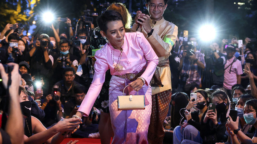 Jatuporn 'New' Saeoueng wears a pink silk dress and shakes hands with other activists on a red carpet at a satirical fashion show protest in Bangkok in 2020