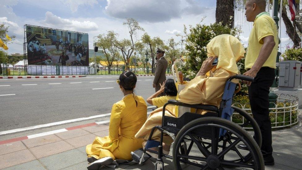 Thai well-wishers watch coronation ceremony of Thai King Maha Vajiralongkorn n a screen