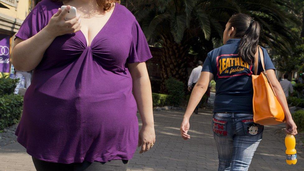 An overweight Mexican woman walking down the street.