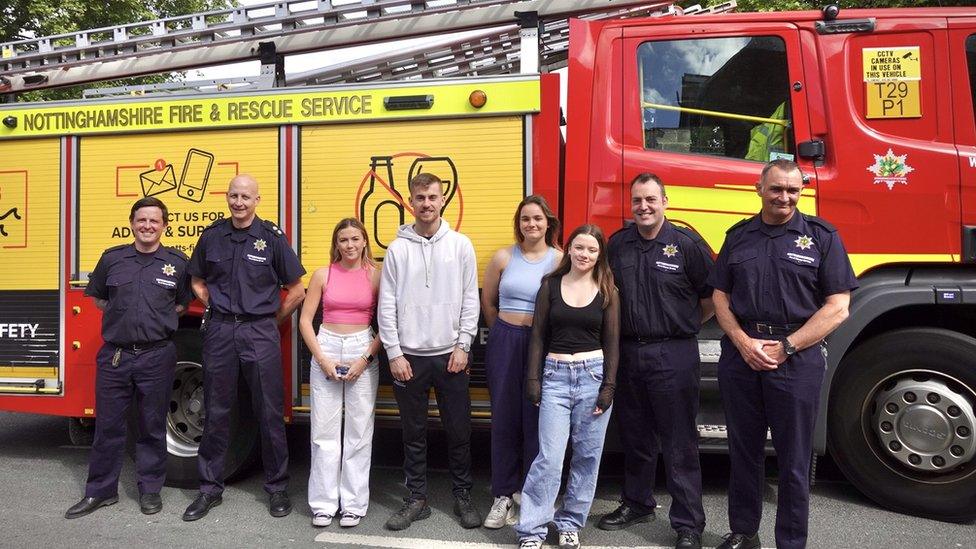 University students and firefighters stand in front of a fire engine