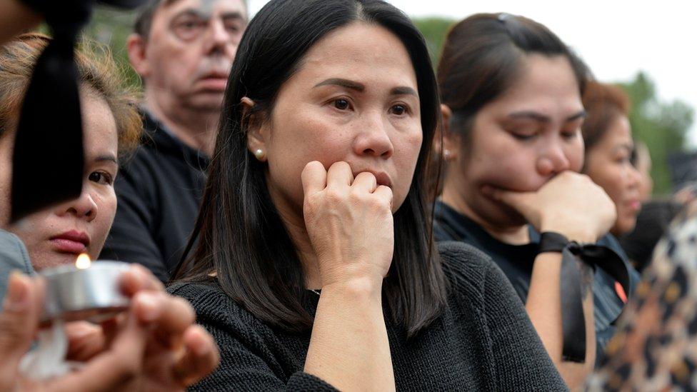 Members of the Filipino community in Cyprus attending a vigil for the victims on April 26. One holds a candle.