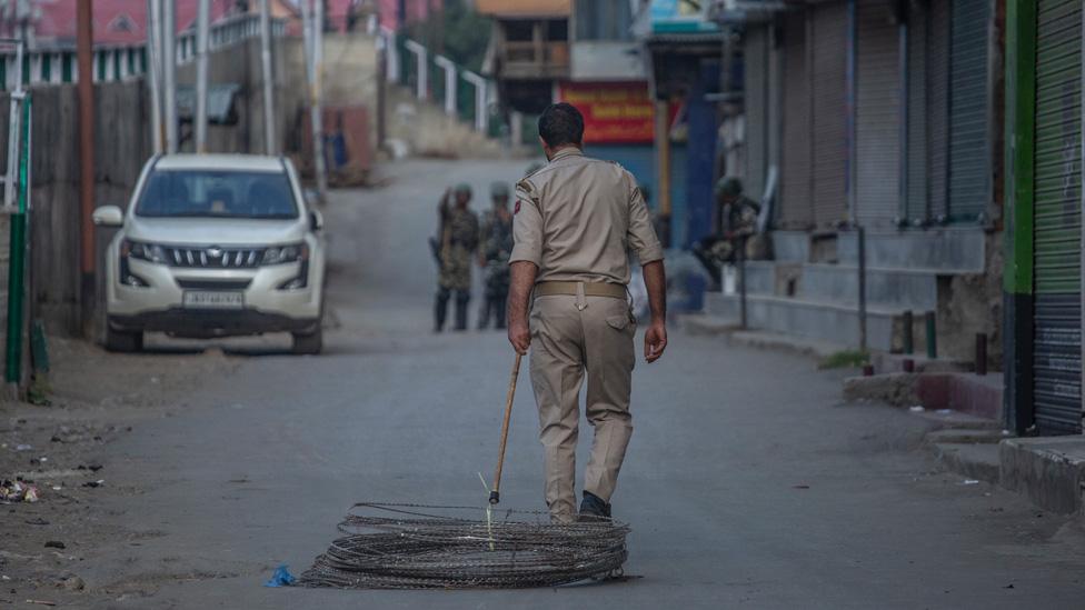 A security officer drags a coil of barbed wire behind him