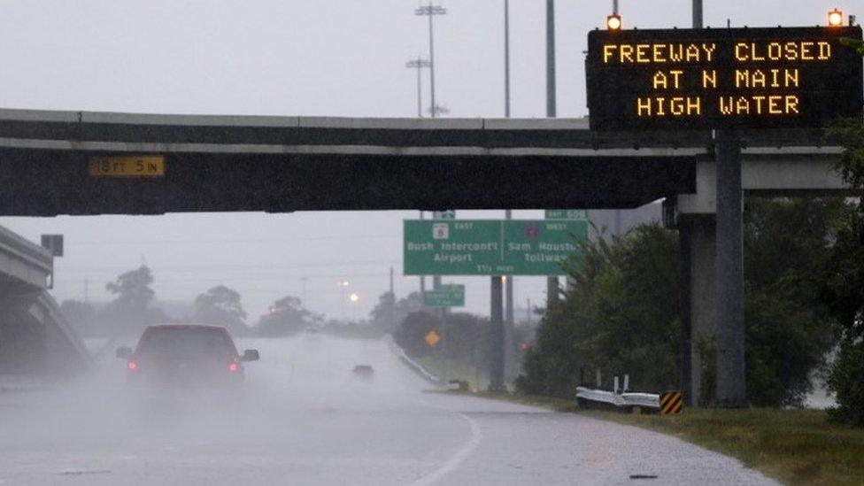 A pick-up truck passes a warning sign on southbound Interstate 45 north of Houston, TX, as heavy rains from the remnants of Hurricane Harvey continue to flood many areas of the city (27 August 2017)