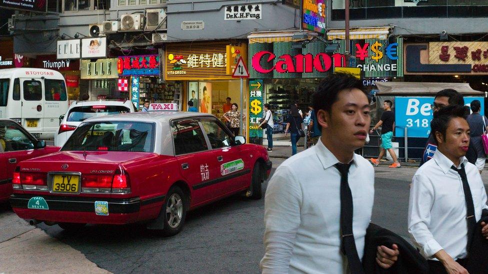 Pedestrians walk past shop fronts in Hong Kong's Tim Sha Tsui district in 2016