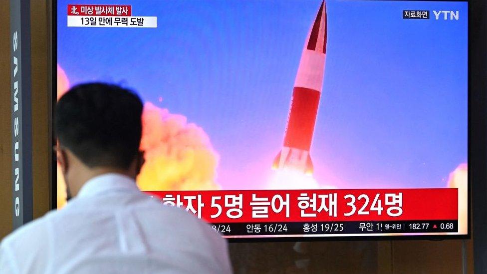 People watch a television news broadcast showing file footage of a North Korean missile test, at a railway station in Seoul on September 28, 2021