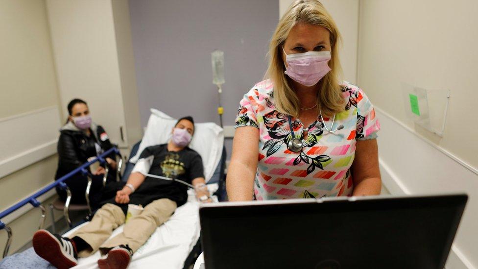 An emergency room nurse (R) treats a hospital patient for flu this month in Escondido, California