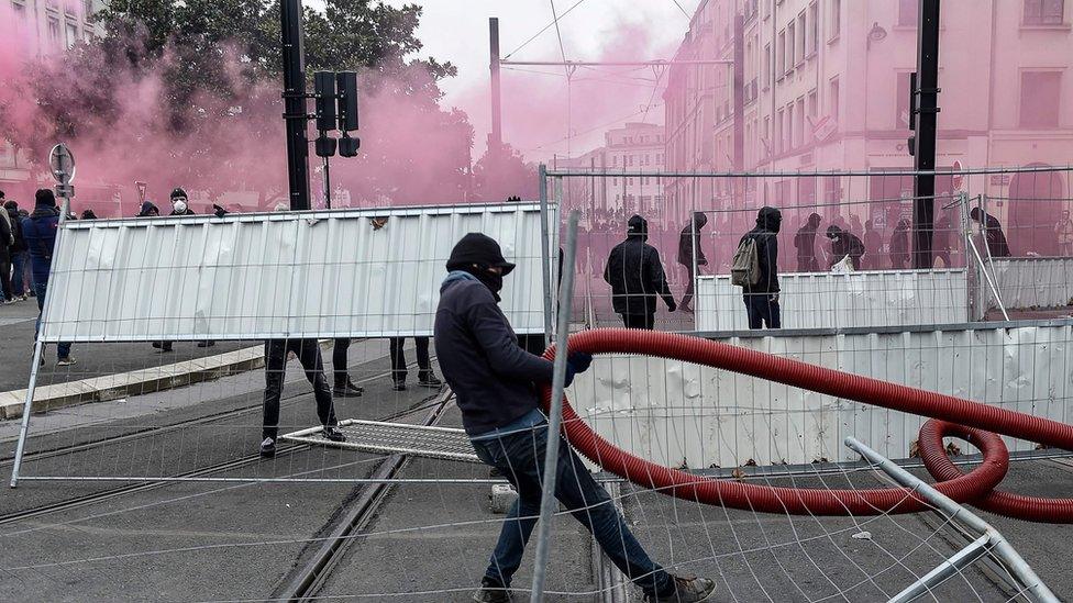 Protesters dressed in black build a barricade amid tear gas smoke during a demonstration to protest against the pension overhauls, in Nantes, on December 5, 2019,