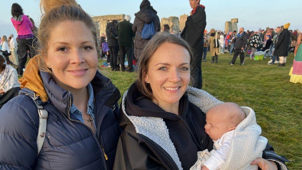 Two women smiling, one holding a baby