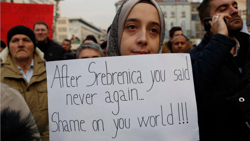 A Bosnian woman holds a banner during a solidarity rally in Sarajevo, Bosnia on 14 December, saying: "After Srebrenica you said never again. Shame on you, world".