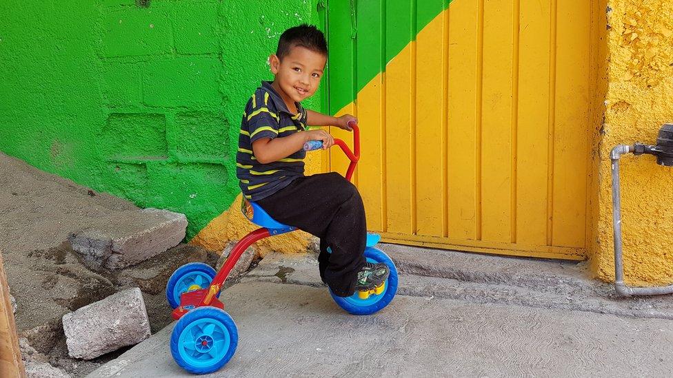 A boy rides a tricycle in Palmitas