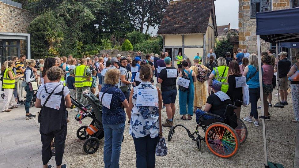 A large group of people standing with signs on their back