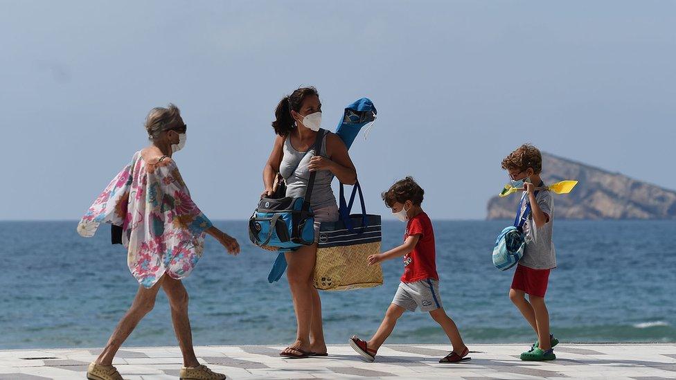 A family heading to the beach in face masks.