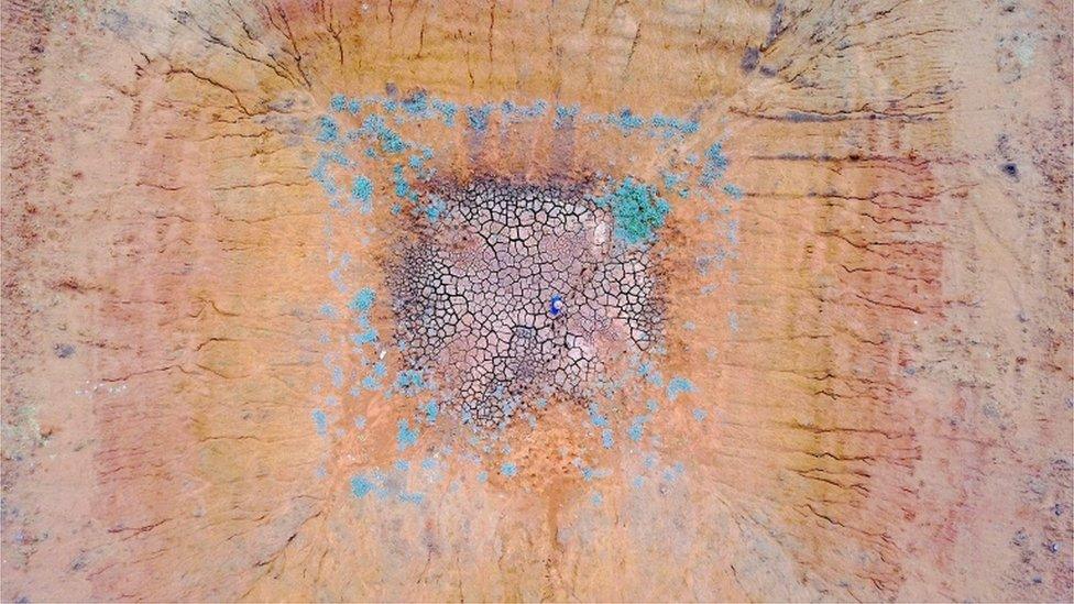 Farmer Ash Whitney stands in the middle of a dried-up dam in a drought-affected paddock on his property located west of the town of Gunnedah in New South Wales, Australia, 3 June 2018