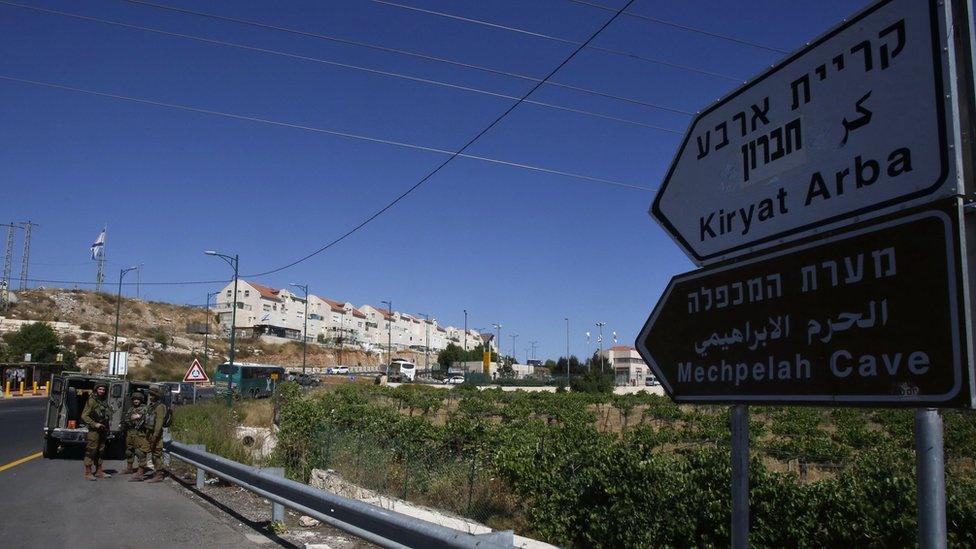 Israeli soldiers stand guard on the road near the Jewish settlement of Kiryat Arba where a 13-year-old Israeli girl was fatally stabbed in her bedroom on 30 June