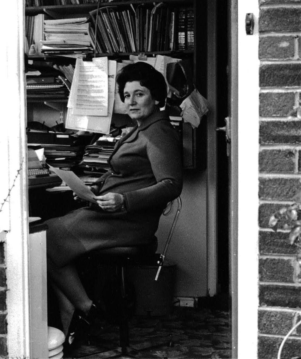 Diane Munday, sitting at a desk in the 1960s