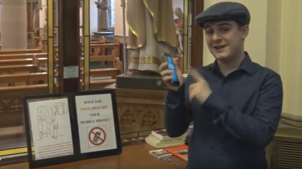 A man in a cap holding his phone in a church porch