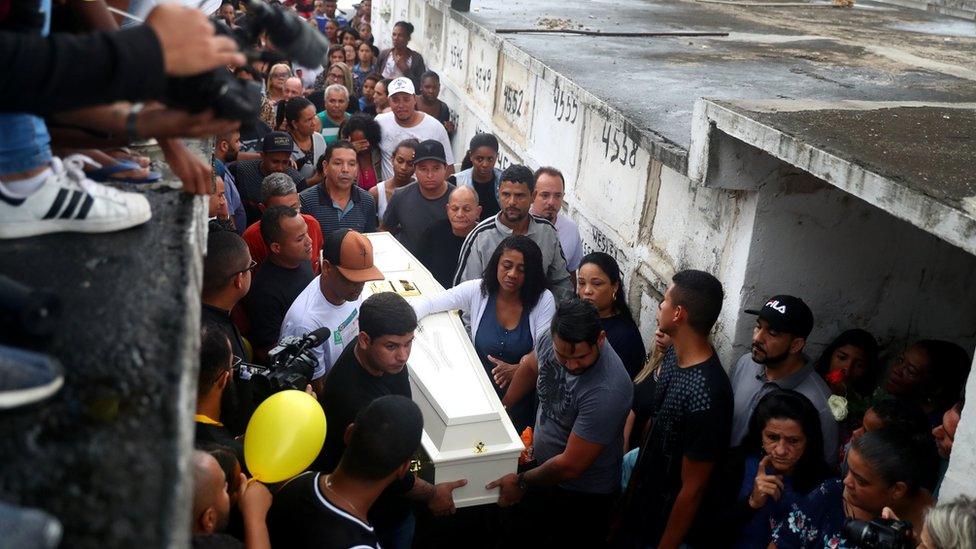 Relatives and friends watch as Ágatha's casket is carried at her funeral