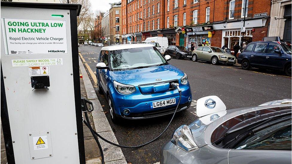 A Nissan Leaf and a Kia Soul charge on a street in Hackney, London.