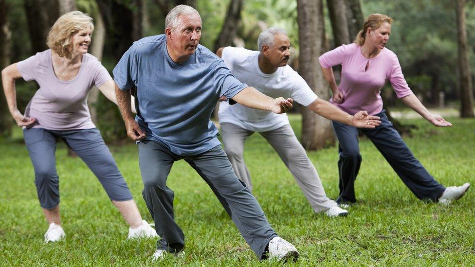 Adults practising tai chi in a park