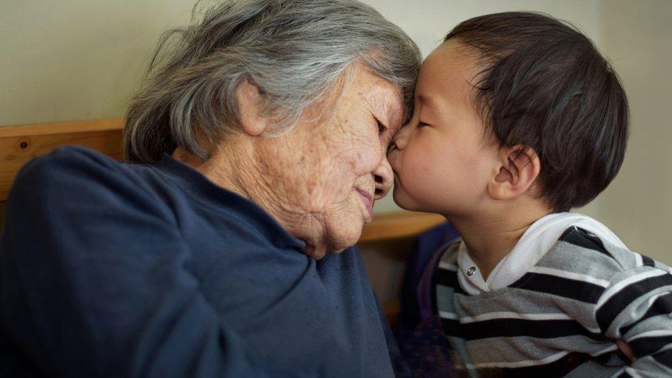 A Chinese child kisses an older woman - stock image