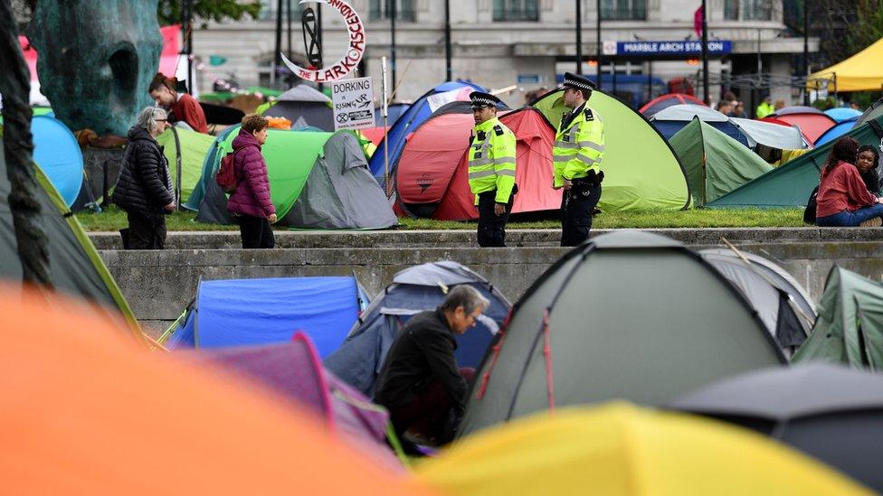 Police officers walk amongst tents at the Extinction Rebellion group's environmental protest camp at Marble Arch in London