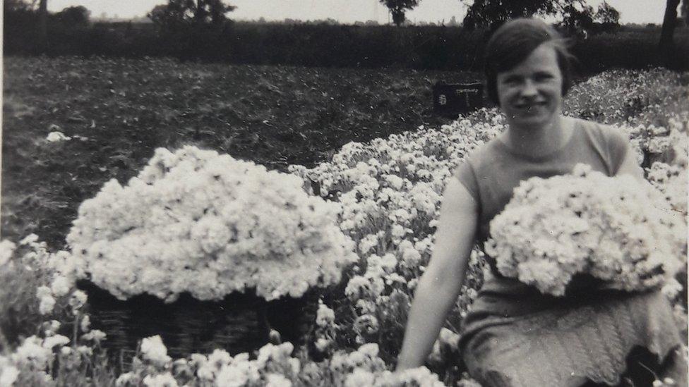 A woman picking flowers in the 1930s