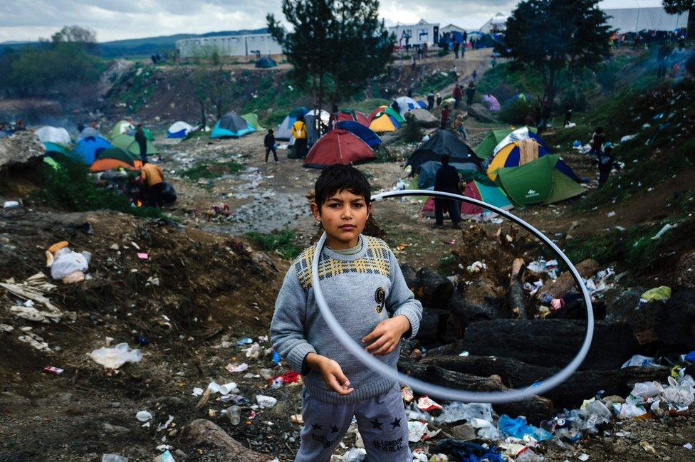 A girl plays with a hula hoop in a makeshift camp