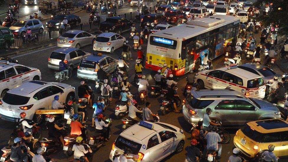 Motorcyclists among rush hour traffic at an intersection in Hanoi