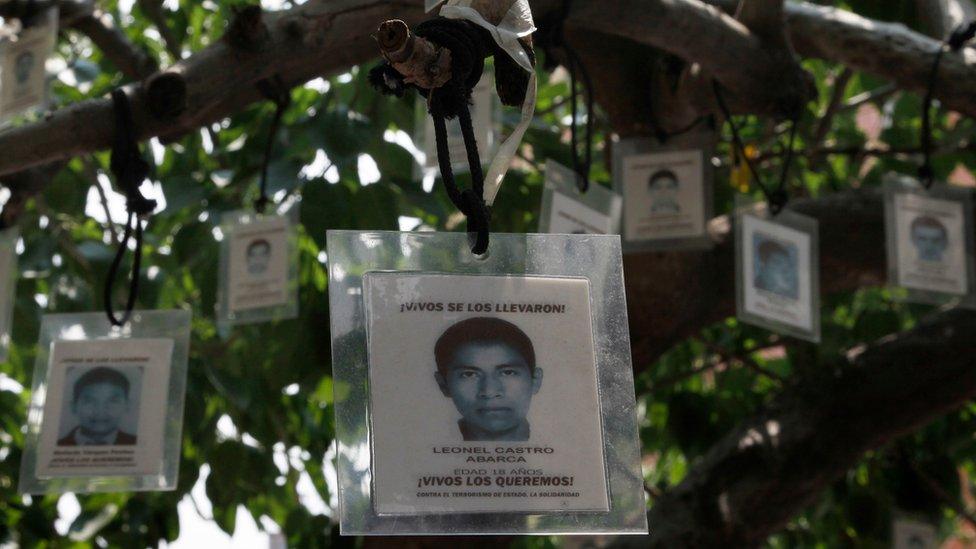 Laminated images of the 43 missing students from the Isidro Burgos rural teachers college hang from a tree in Mexico City, Friday, Aug. 26, 2016.