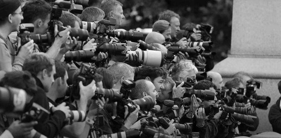 A still from the Harry & Meghan trailer apparently showing pictures of the paparazzi hounding them, which were in fact taken in 2011