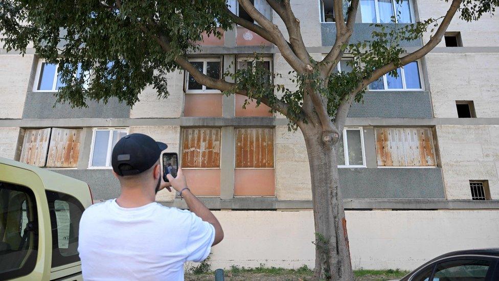 A man takes pictures of the building in Marseille where a woman was shot inside her flat