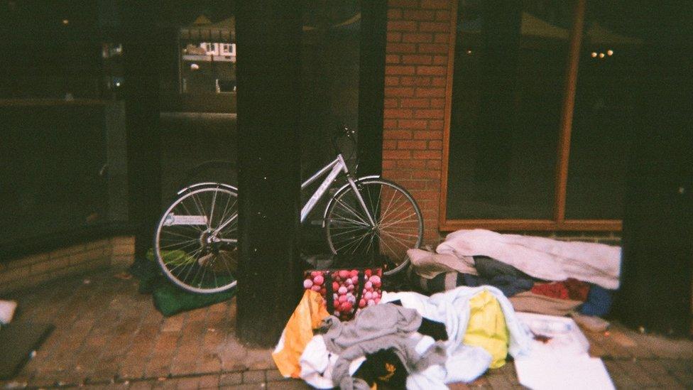 A bike, bags and bedding on the street outside a building