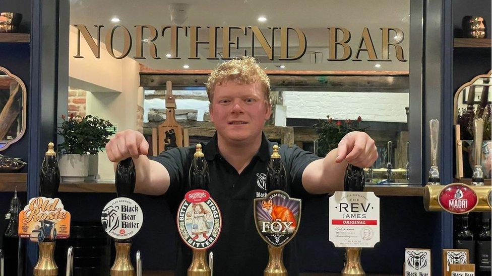 A ginger man behind a bar