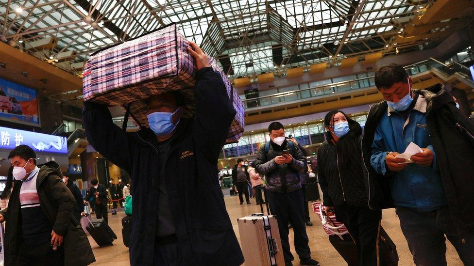 People walk with their luggages at a railway station during the annual Spring Festival travel rush ahead of the Chinese Lunar New Year, as the coronavirus disease (COVID-19) outbreak continues, in Beijing, China January 13, 2023