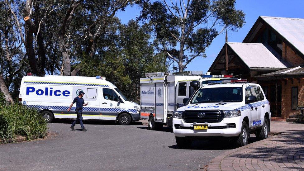 Police personnel work near the entrance to the walking track where a landslide killed two people and injured two others in the Blue Mountains west of Sydney