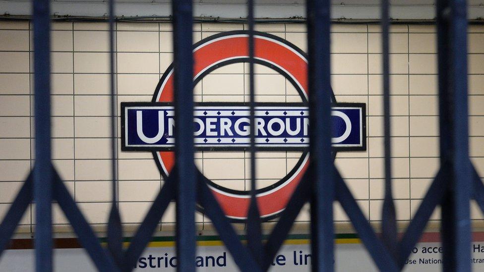 An Underground sign seen through closed gates at the entrance to Paddington Station, London