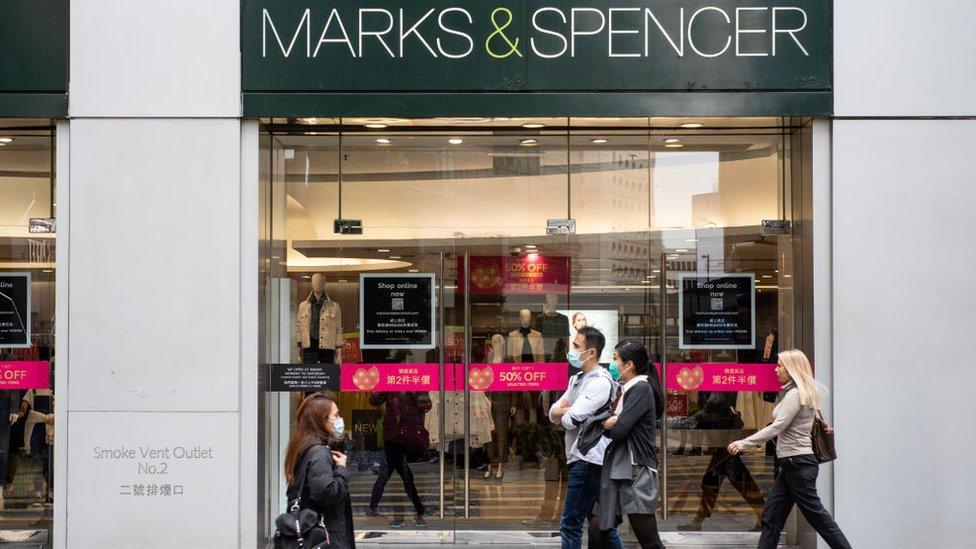 People walk past Marks & Spencer in Hong Kong