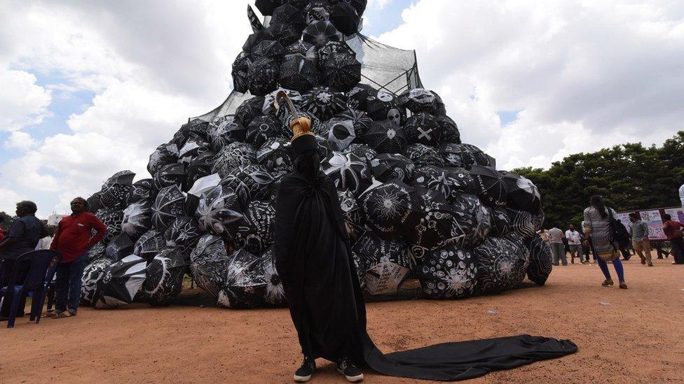 A protestor stands in front of black umbrellas