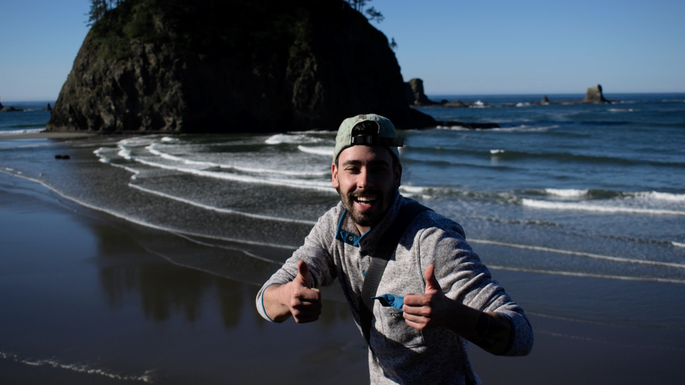 Matthew Dippel puts thumbs up on a beach