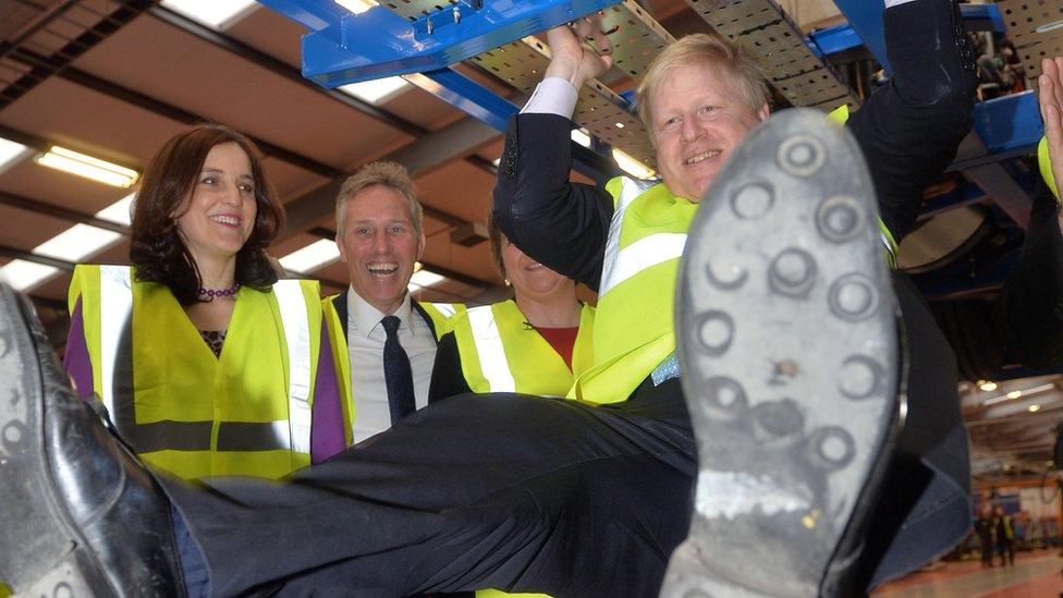 London Mayor Boris Johnson swings from bus structure