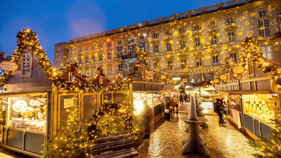 People stroll past Christmas lights and decorations at the outdoor Christmas market at Humboldt Forum in central Berlin, Germany