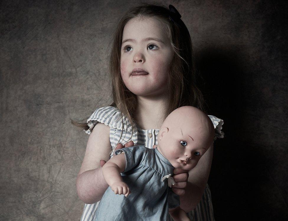 A young girl holds a doll